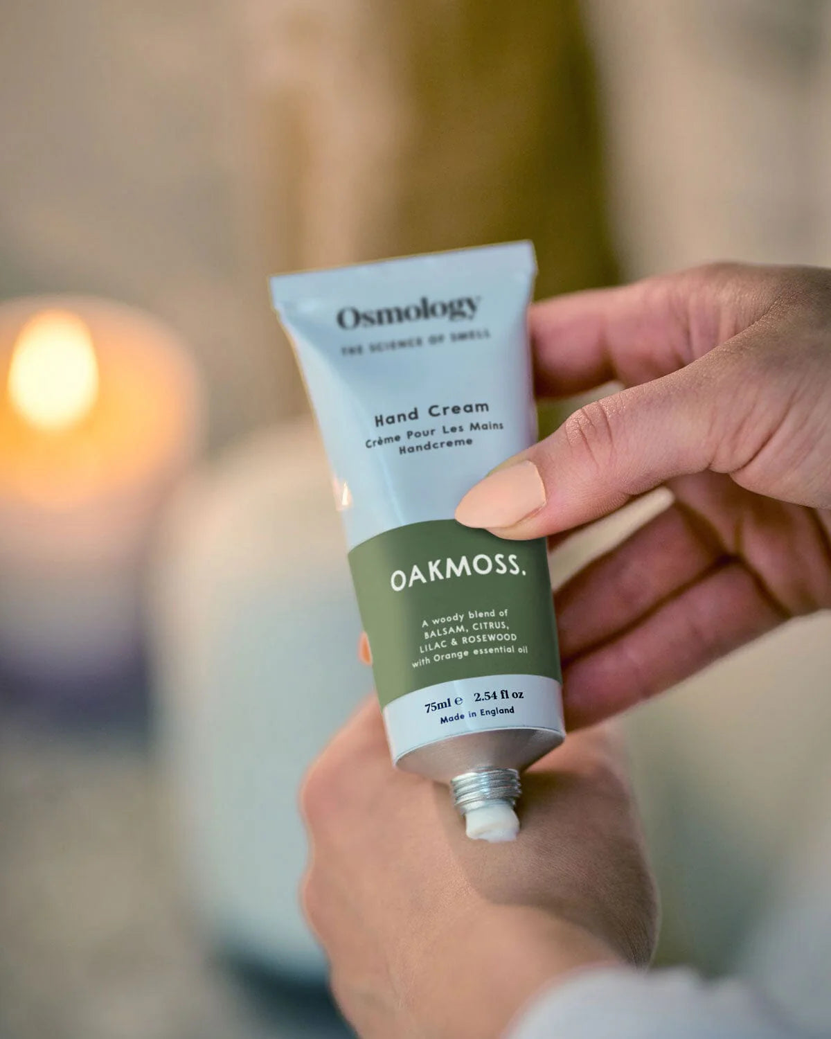 Osmology hand cream tube held by a person with a blurred background