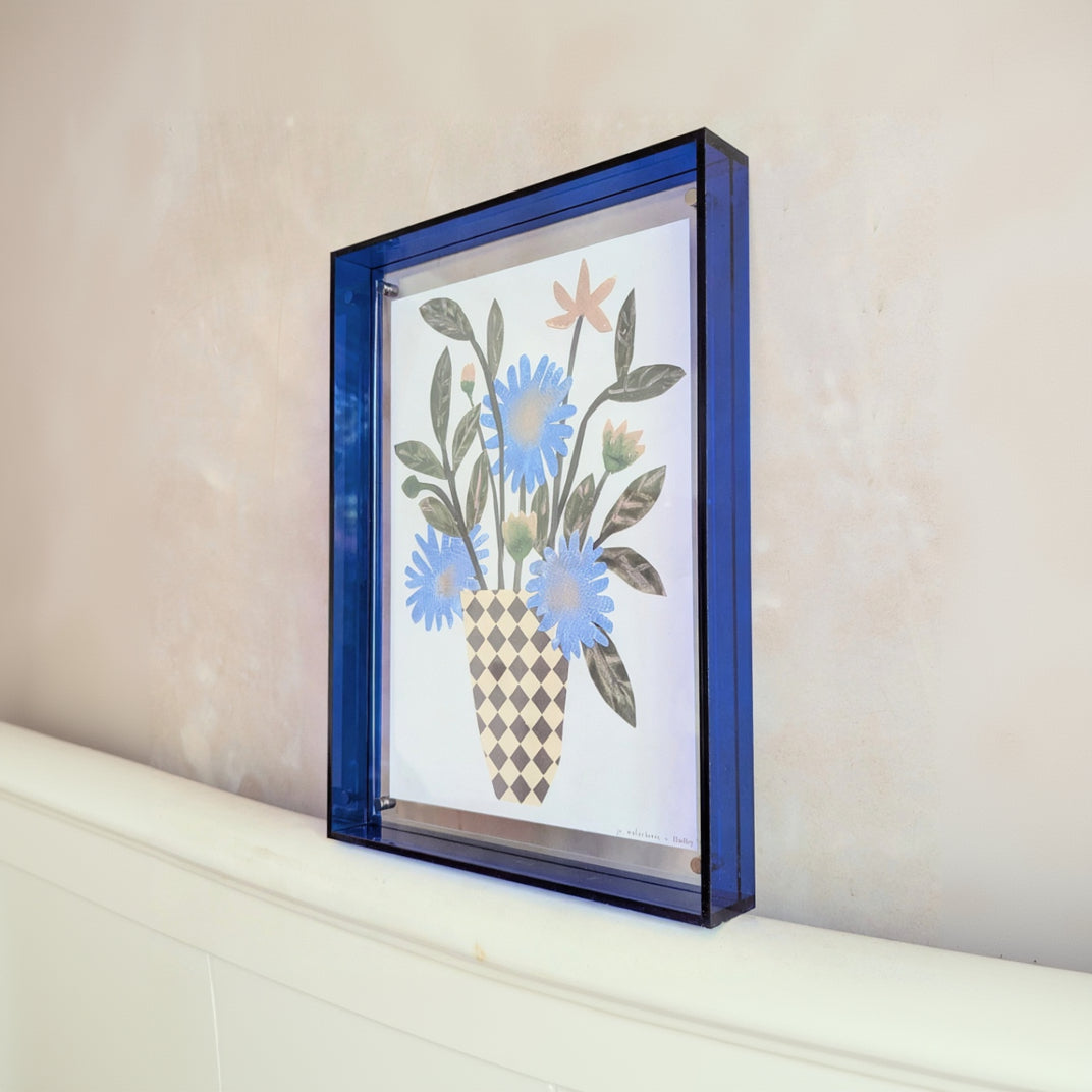 Decorative wall art with floral design in a blue frame on a neutral background
