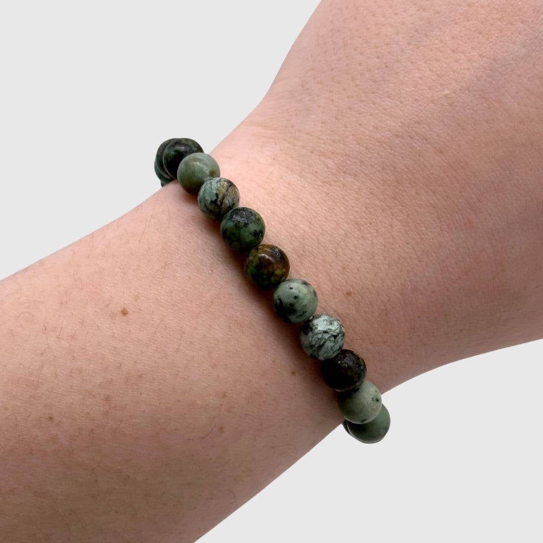 African Turquoise dark teal beaded bracelet on a wrist against a white background