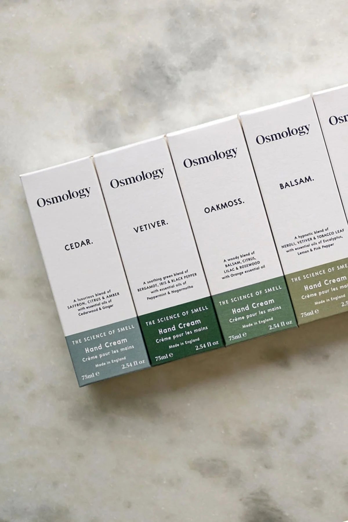 Osmology hand cream boxes on a textured surface
