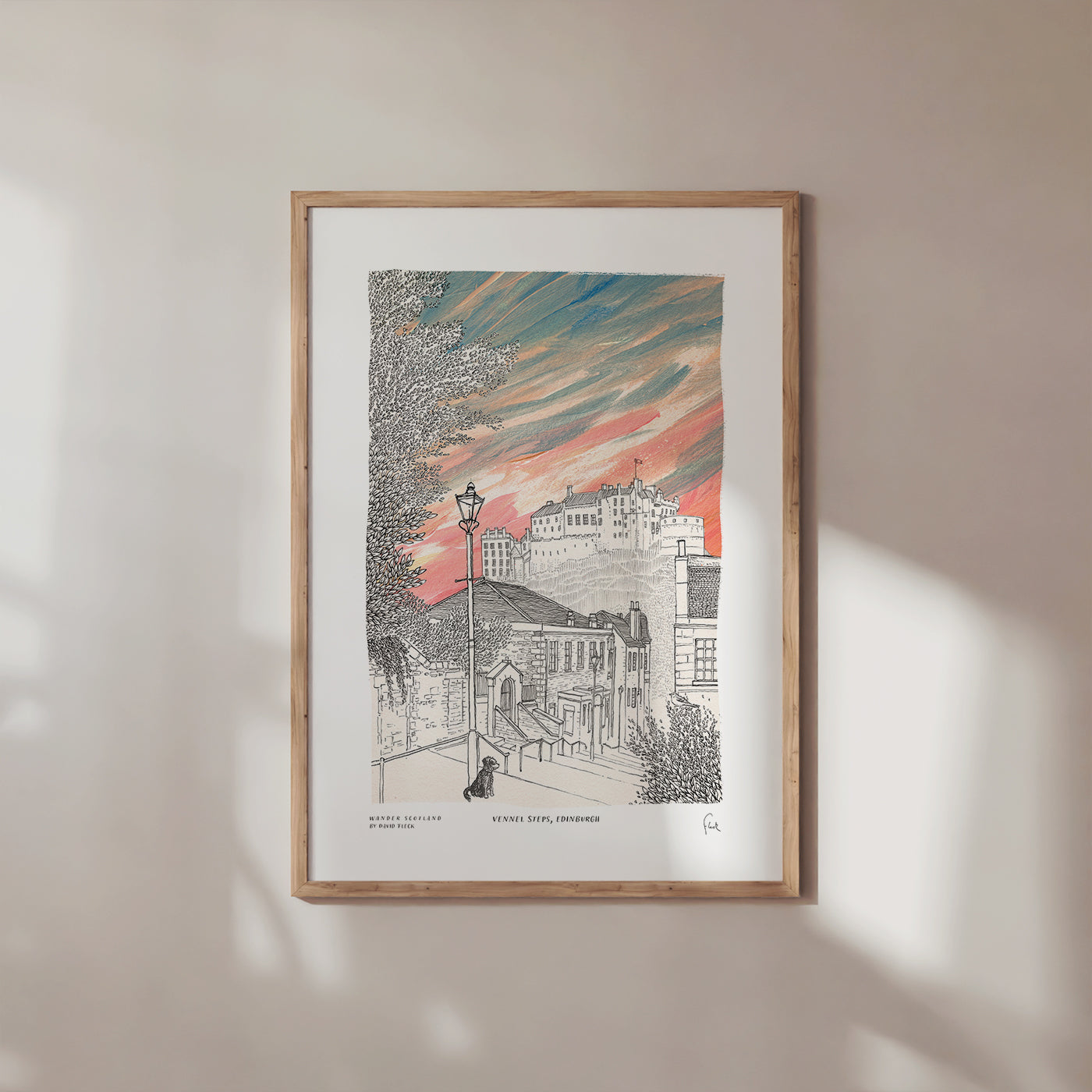 Framed artwork of an Edinburgh cityscape with a colorful sky on a beige wall.