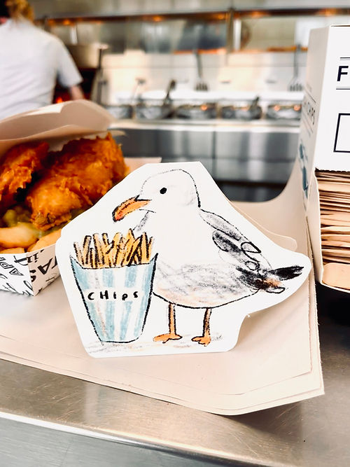 Seagull holding a basket of chips with a blurred kitchen background